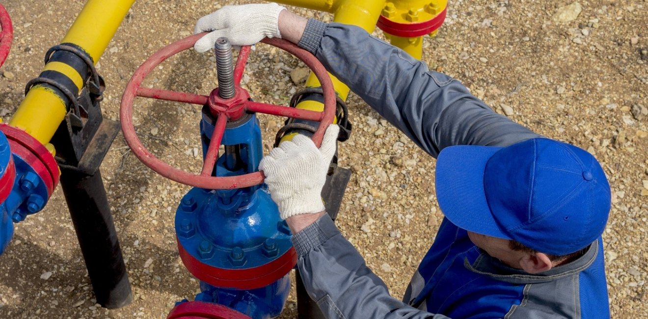 Image of a worker opening, closing the shut-off valves at the gas pumping station. Part of the photo is blurry.