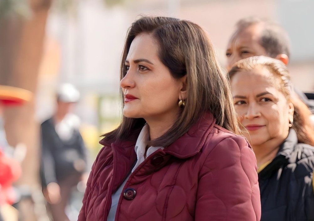 Photo of candidate Alma Alcaraz Hernández looking towards the left, with another woman positioned in the background.